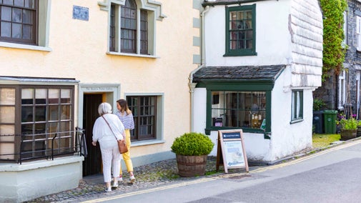 Two visitors walking through the doorway of the Beatrix Potter Gallery, Hawkshead